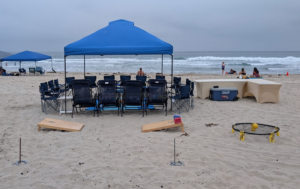 Beach umbrella set up with comfortable seating and towels along the San Diego coastline.
