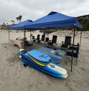 Family beach setup with large canopy, chairs, towels, and cooler at Crown Point in Mission Bay.