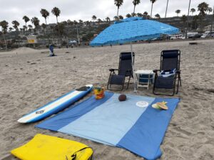 Professionally arranged beach setup with Umbrella, chairs, towels, and cooler ready for guests.