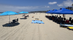 Beach event rental with multiple canopies, chairs, tables, and games for a corporate gathering.